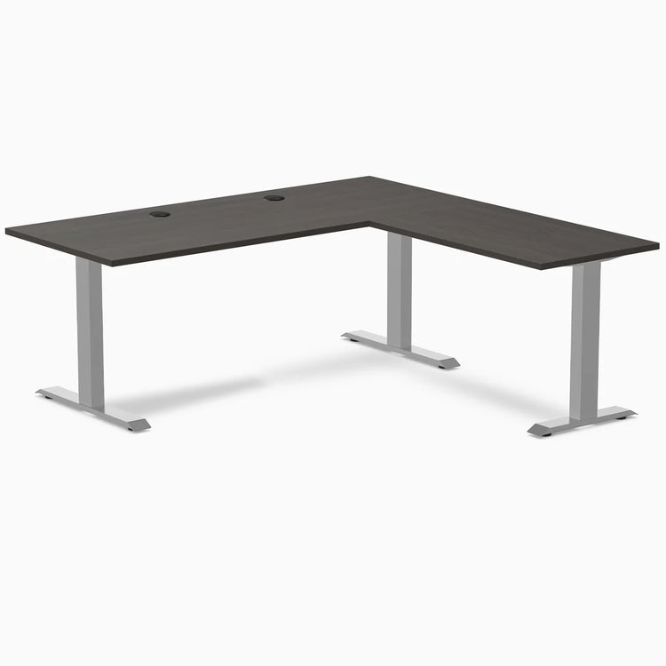 Burnished wood laminate L-shape office desk with gray steel frame and grommets.