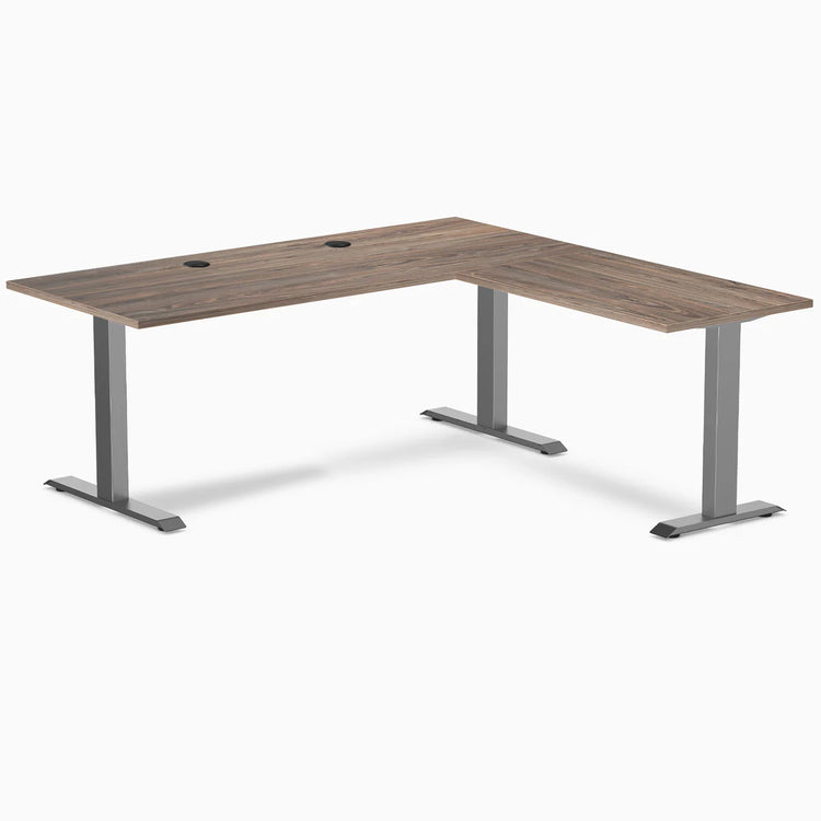 Desky Zero L-shape office desk with natural walnut laminate top, grommets, and space gray steel frame.