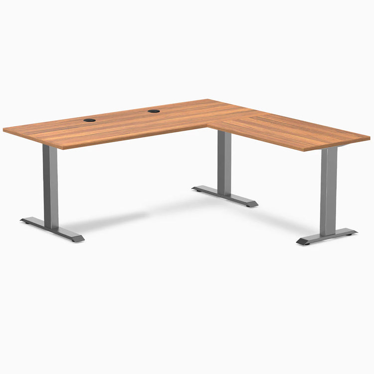 Prime Oak Desky Zero Laminate L-shape office desk with Space Gray steel frame and grommets.