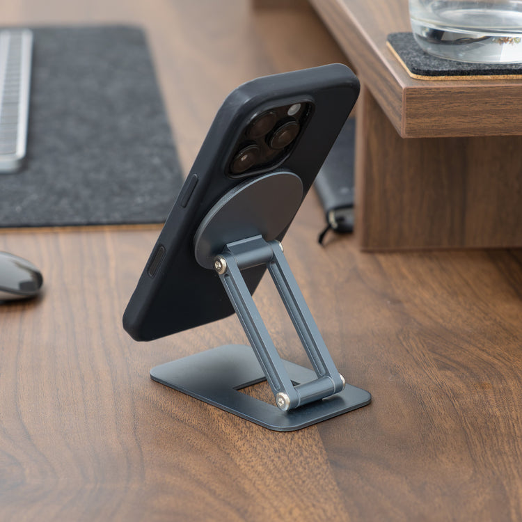 Phone stand holding a smartphone on a wooden desk with office items in the background