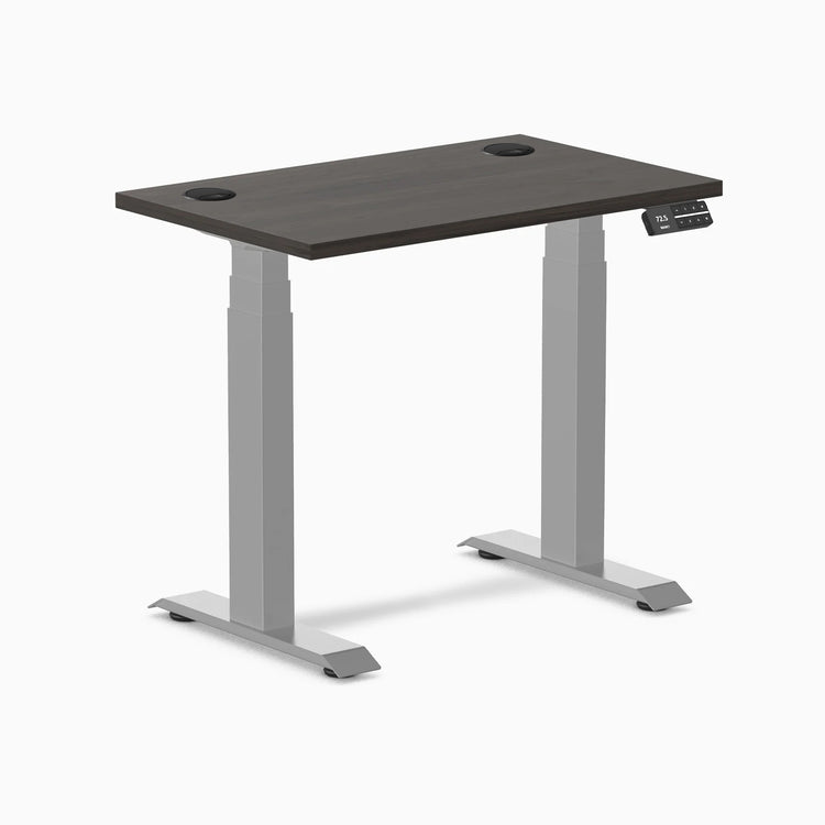 Desky Dual Mini sit-stand desk with burnished wood top, gray frame, and grommets.