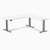 White laminate L-shape sit-stand desk with space gray triple electric motors and grommets.