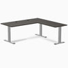 Burnished wood laminate L-shape office desk with gray steel frame and grommets.