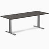 Desky Zero fixed height office desk with burnished wood laminate top, space gray steel frame, and grommets.