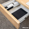 Minimal under-desk drawer in white ash wood, open to reveal white interior with tablet and remotes.