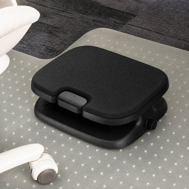 A black ergonomic footrest with a textured fabric top and adjustable base