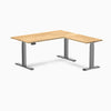 White Oak L-Shape Sit Stand Desk with Space Gray frame and control panel.